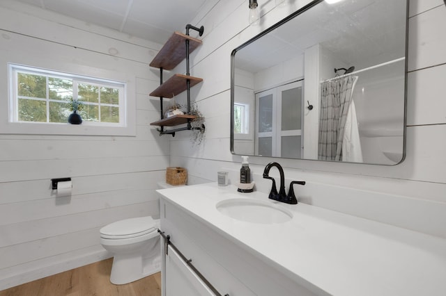 bathroom featuring a shower with curtain, vanity, hardwood / wood-style flooring, toilet, and wood walls