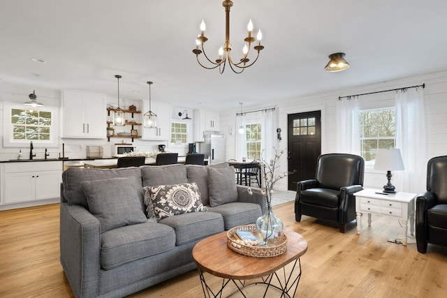 living room featuring a notable chandelier, sink, and light hardwood / wood-style flooring