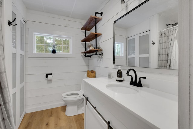 bathroom with hardwood / wood-style floors, vanity, wood walls, and toilet