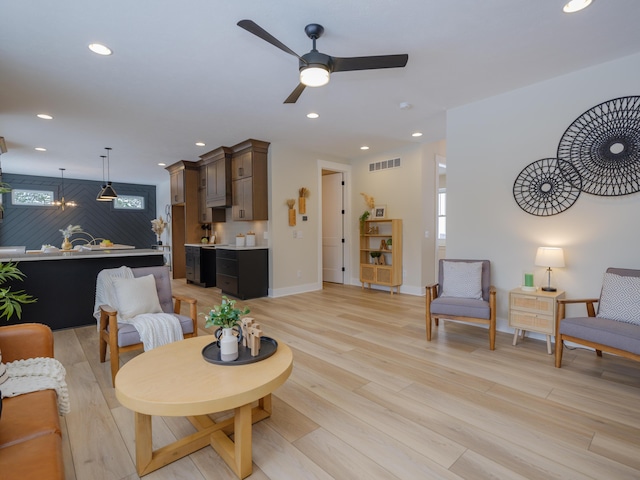 living room with light hardwood / wood-style flooring, ceiling fan, and a healthy amount of sunlight