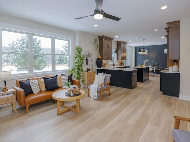 living room featuring ceiling fan, light wood-type flooring, and sink