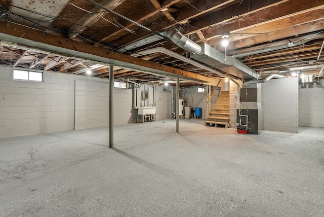 basement featuring heating unit, water heater, and sink