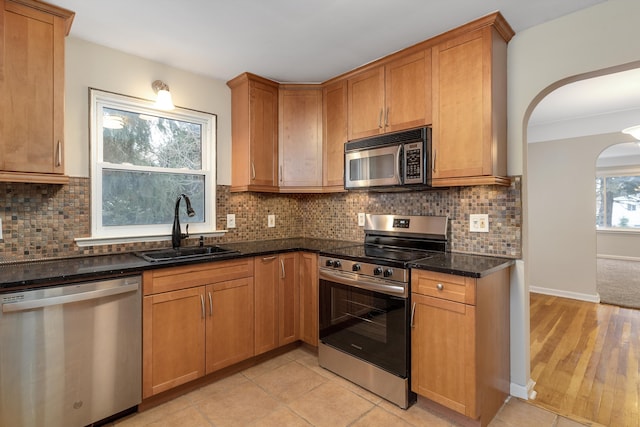 kitchen featuring tasteful backsplash, dark stone countertops, sink, and appliances with stainless steel finishes