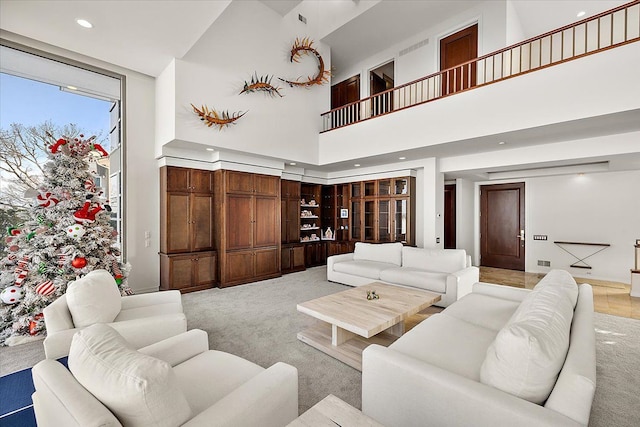 carpeted living room featuring a towering ceiling