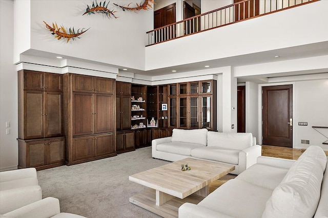 living room featuring light colored carpet and a towering ceiling