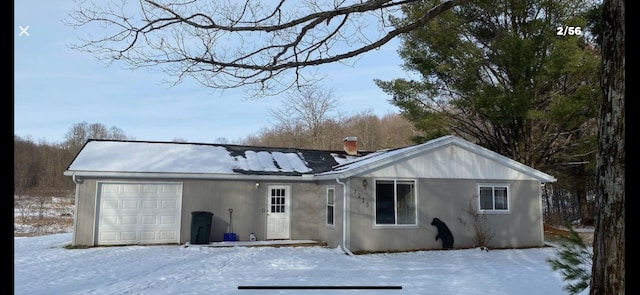 snow covered rear of property featuring a garage