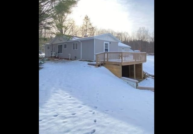 snow covered rear of property with a deck