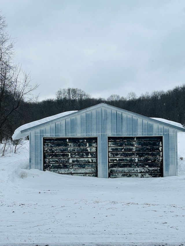 snow covered structure featuring a garage