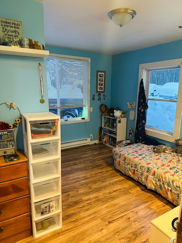 bedroom with baseboard heating and hardwood / wood-style flooring