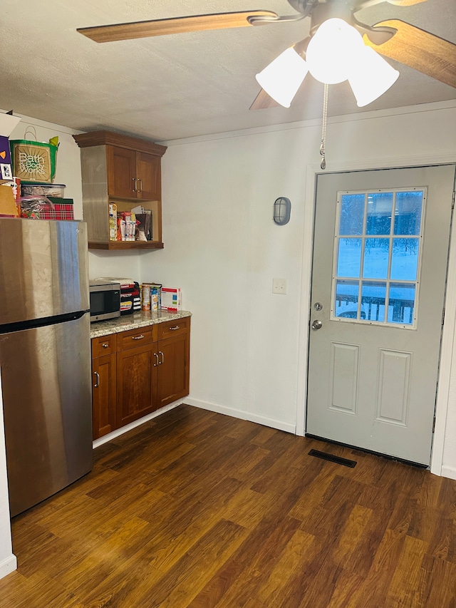 kitchen with a textured ceiling, stainless steel appliances, and dark hardwood / wood-style floors