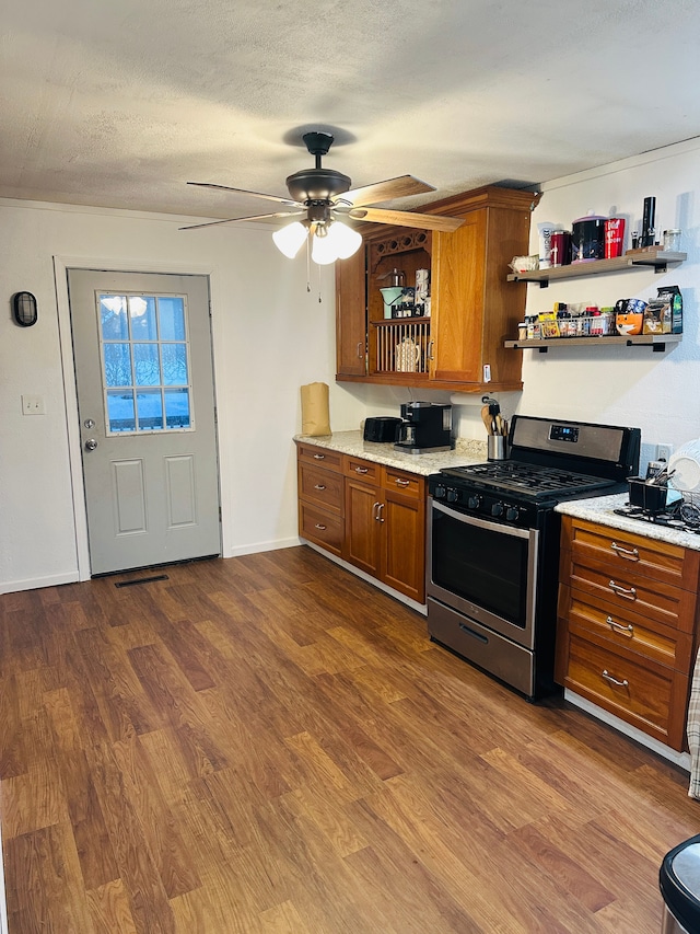 kitchen with a textured ceiling, stainless steel gas stove, ceiling fan, and dark wood-type flooring