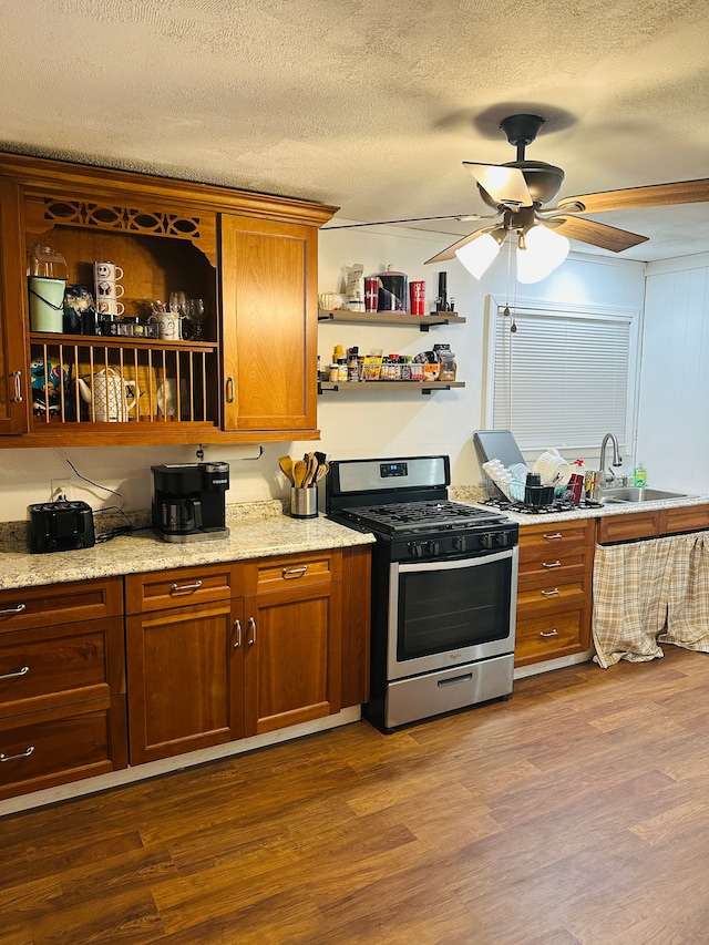 kitchen featuring stainless steel range with gas cooktop, sink, wood-type flooring, and a textured ceiling