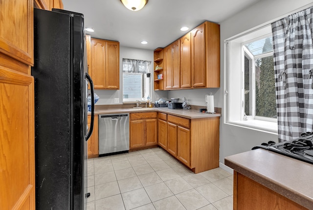 kitchen featuring dishwasher, sink, black refrigerator, and light tile patterned flooring