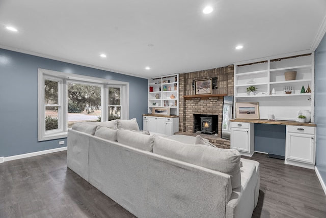 living room with built in shelves, crown molding, built in desk, dark hardwood / wood-style floors, and a wood stove