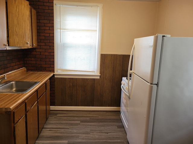 kitchen with dark hardwood / wood-style flooring, sink, range, white fridge, and wood walls