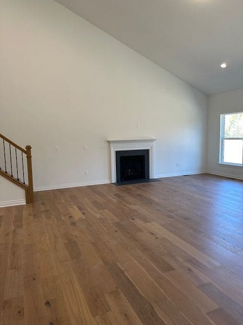 unfurnished living room with hardwood / wood-style flooring and vaulted ceiling