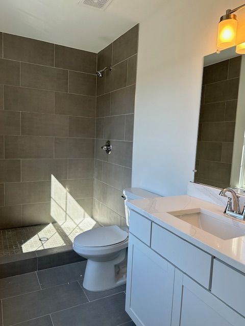 bathroom featuring tile patterned flooring, vanity, and tiled shower