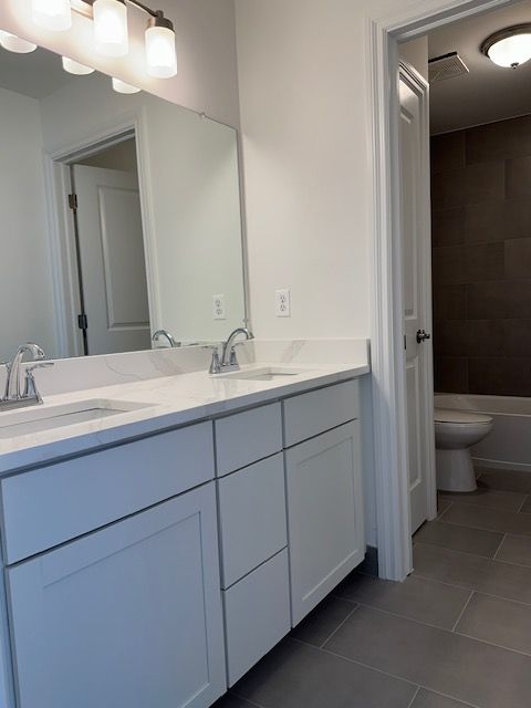 full bathroom featuring tile patterned flooring, vanity, toilet, and tiled shower / bath combo