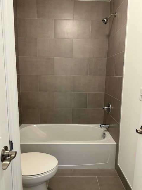 bathroom with tile patterned flooring, tiled shower / bath, and toilet