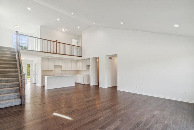 unfurnished living room with a high ceiling and dark hardwood / wood-style floors