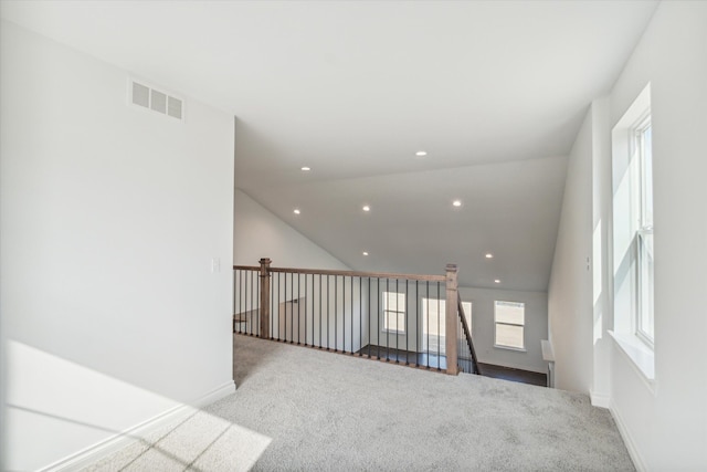 spare room featuring light carpet and lofted ceiling