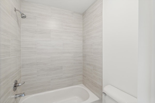 bathroom featuring tiled shower / bath combo and toilet