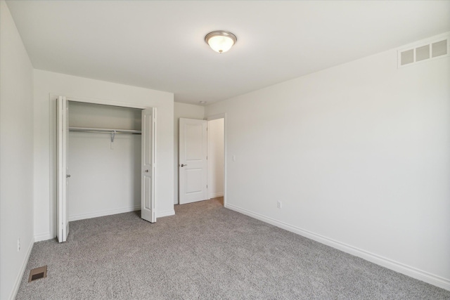 unfurnished bedroom with light carpet and a closet