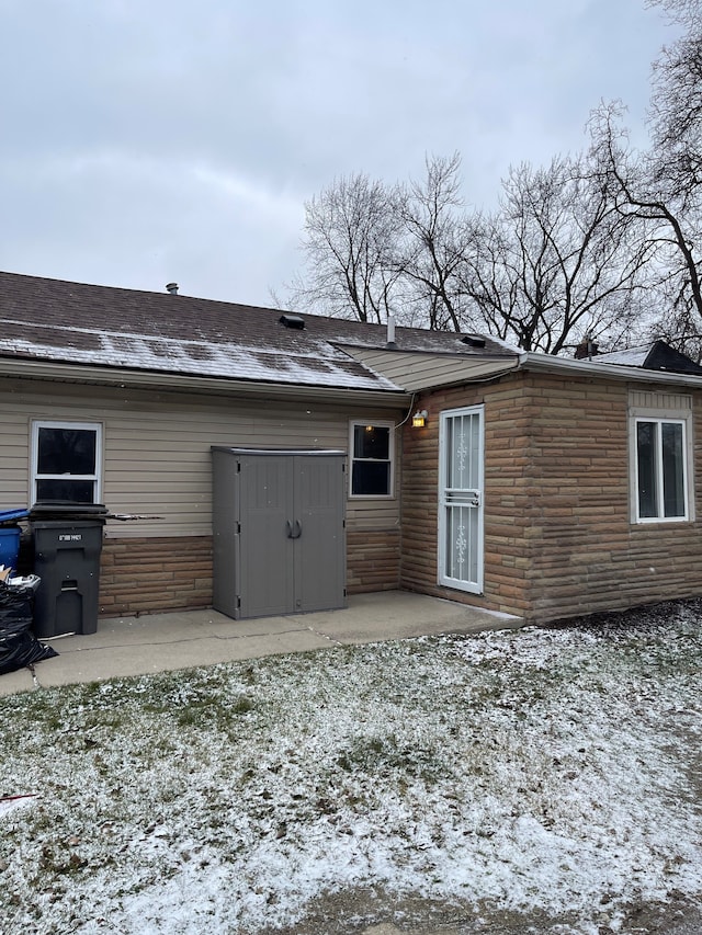 snow covered house featuring a patio area