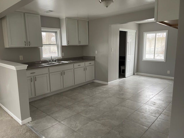 kitchen with light tile patterned flooring, white cabinetry, and sink