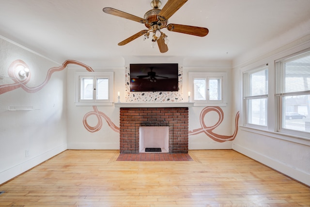 unfurnished living room featuring ceiling fan, light hardwood / wood-style flooring, ornamental molding, and a brick fireplace