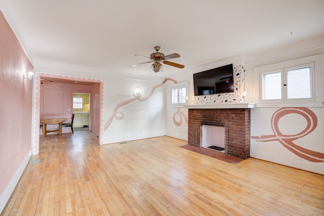 unfurnished living room with a fireplace, light hardwood / wood-style flooring, ceiling fan, and crown molding