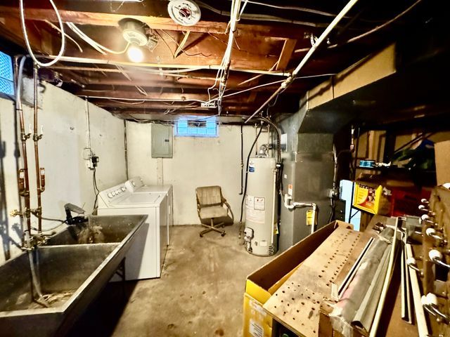 basement with water heater, washing machine and dryer, heating unit, and electric panel