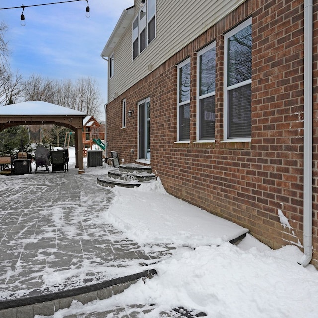 view of snowy exterior with a gazebo and a playground