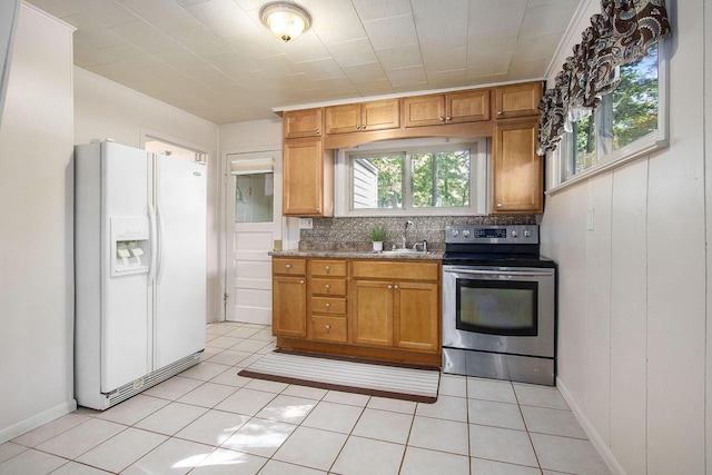 kitchen with sink, stainless steel electric range, plenty of natural light, white fridge with ice dispenser, and backsplash