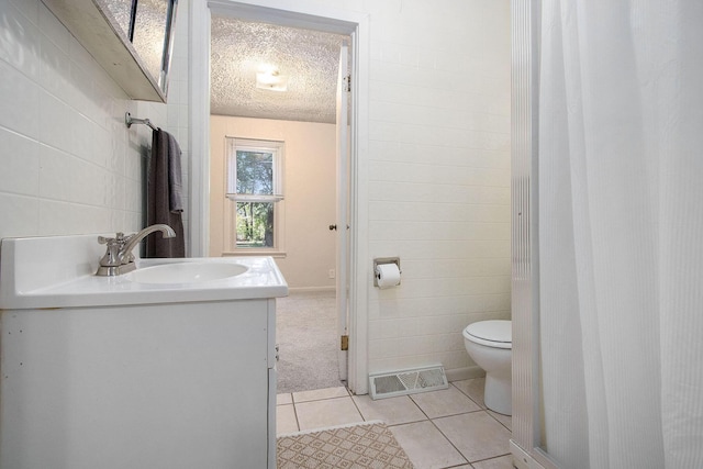 bathroom featuring tile patterned floors, toilet, tile walls, a textured ceiling, and vanity