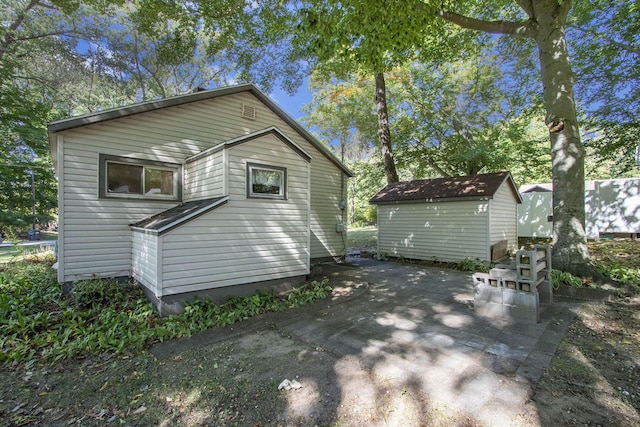 back of property featuring a shed and a patio area