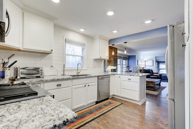 kitchen featuring kitchen peninsula, stainless steel appliances, sink, hardwood / wood-style flooring, and white cabinets