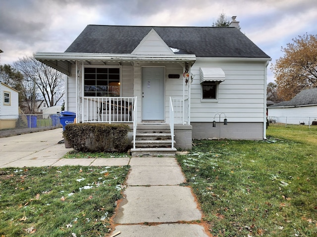 bungalow with covered porch and a front yard