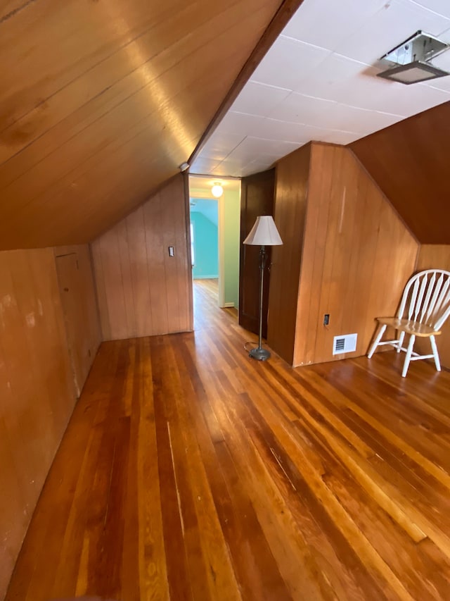 bonus room featuring wooden walls, vaulted ceiling, and hardwood / wood-style flooring