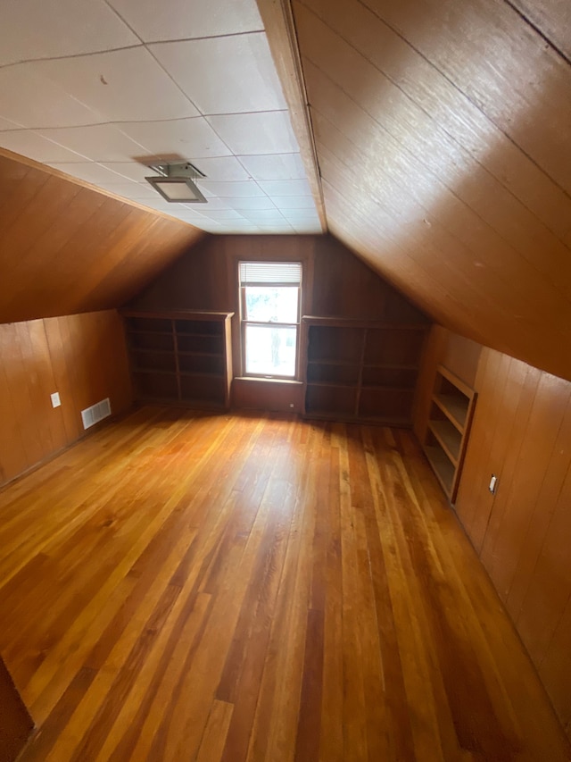 bonus room with hardwood / wood-style floors, wooden walls, and vaulted ceiling