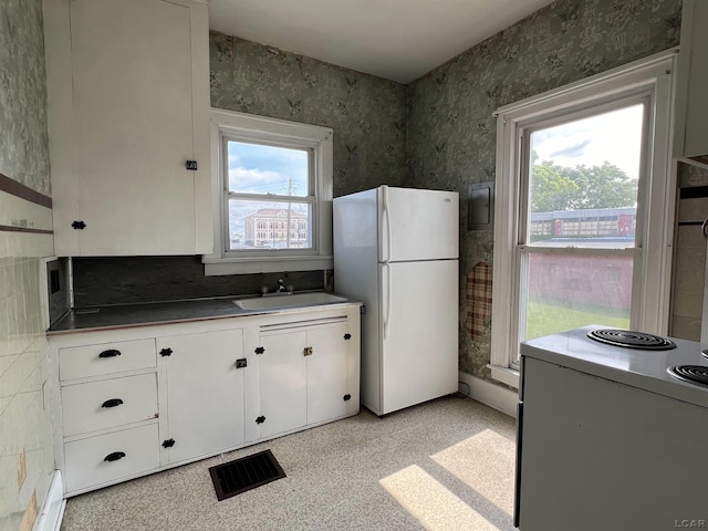 kitchen with white cabinets, range, white fridge, and sink