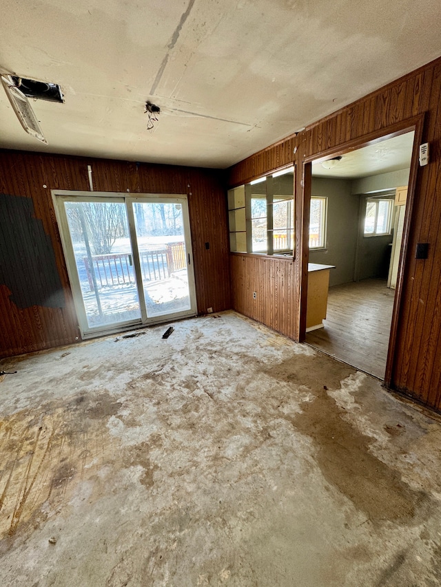 unfurnished living room featuring wood walls