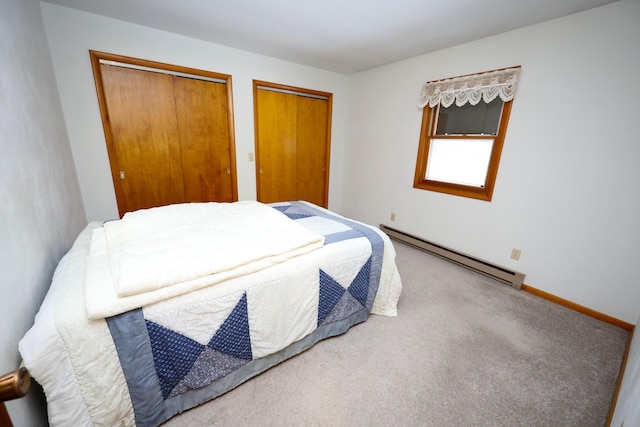 bedroom with carpet floors, a baseboard radiator, and two closets