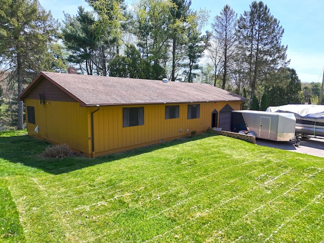 exterior space with roof with shingles, a chimney, a front lawn, and a garage