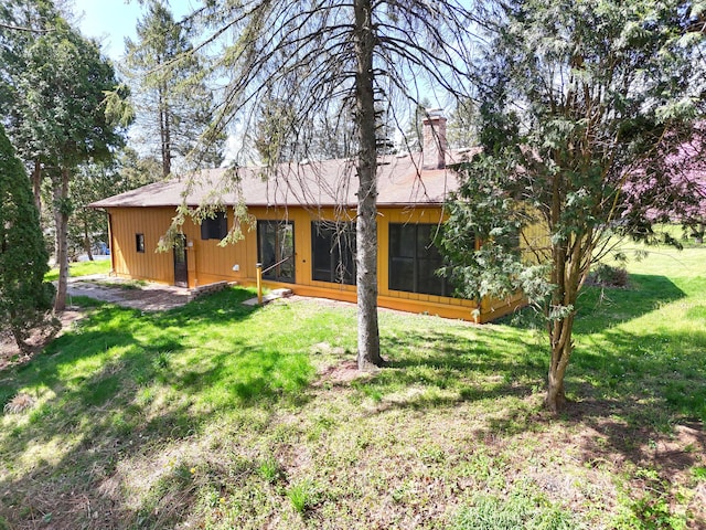 back of property with a yard and a chimney