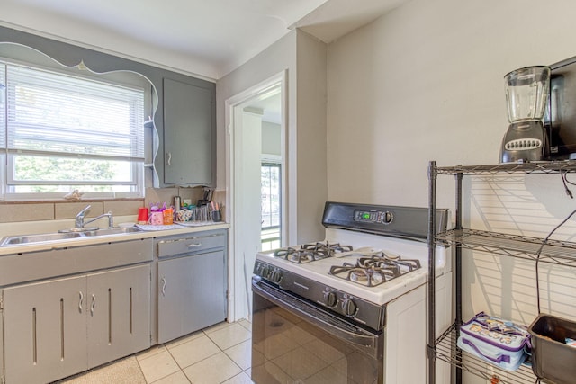 kitchen with white range with gas stovetop, light tile patterned floors, gray cabinets, and sink