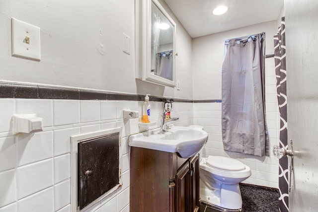 bathroom featuring vanity, toilet, and tile walls