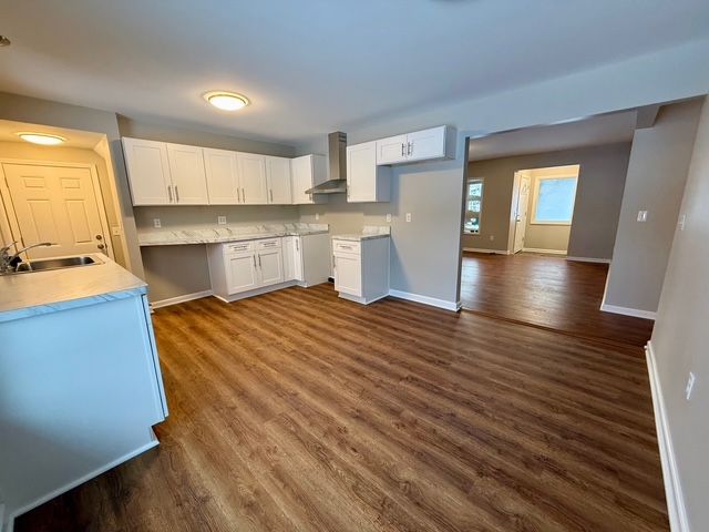 kitchen featuring white cabinets, dark hardwood / wood-style flooring, wall chimney exhaust hood, and sink