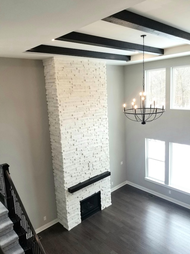 unfurnished living room featuring a notable chandelier, beam ceiling, dark hardwood / wood-style floors, and a fireplace