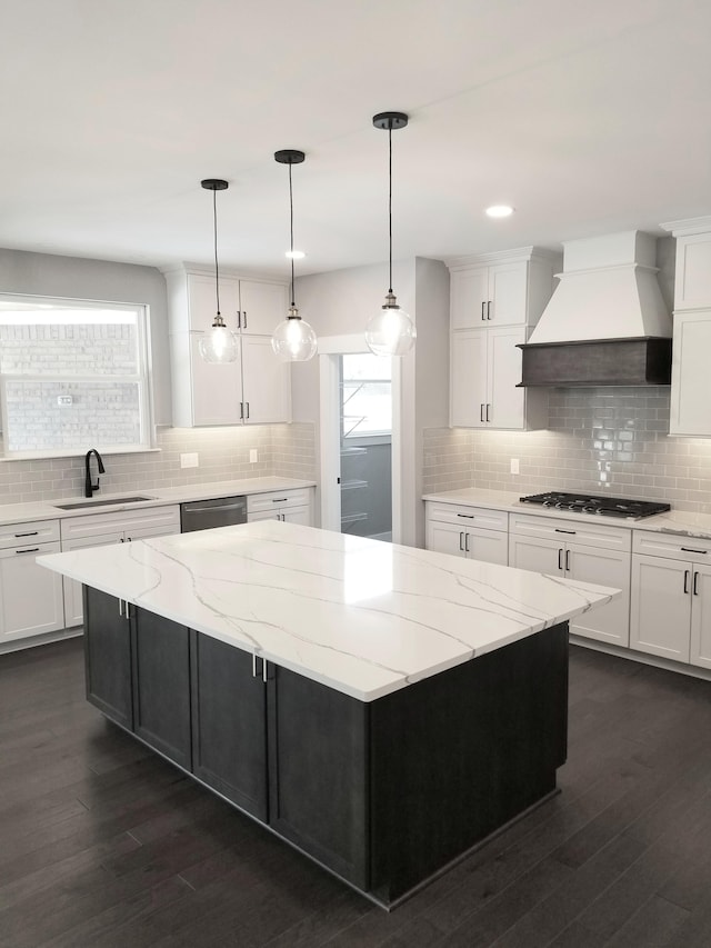 kitchen featuring custom range hood, a spacious island, sink, pendant lighting, and dishwasher